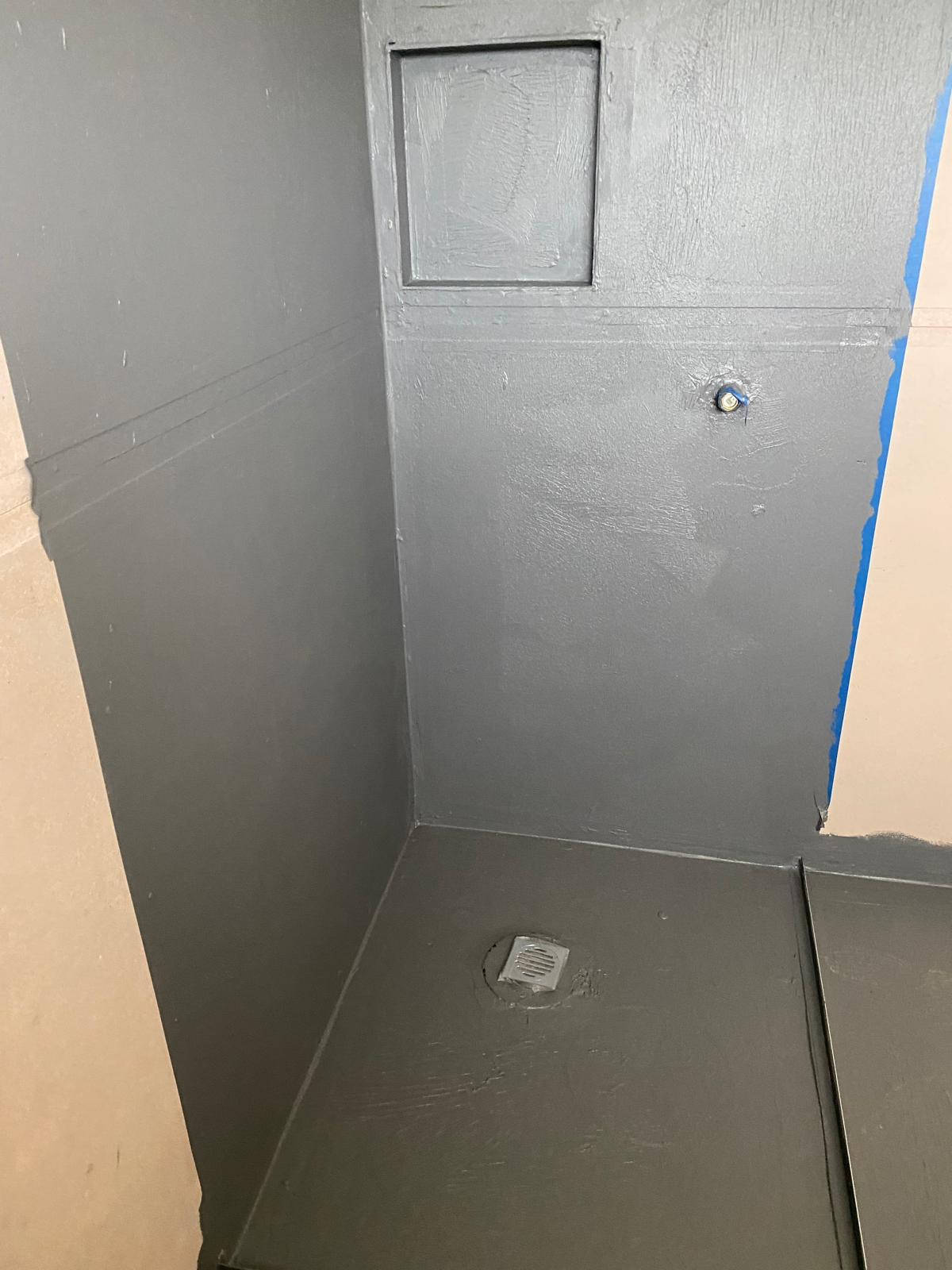 Shower recess fully waterproofed with grey membrane, niche and floor drain ready for tiling